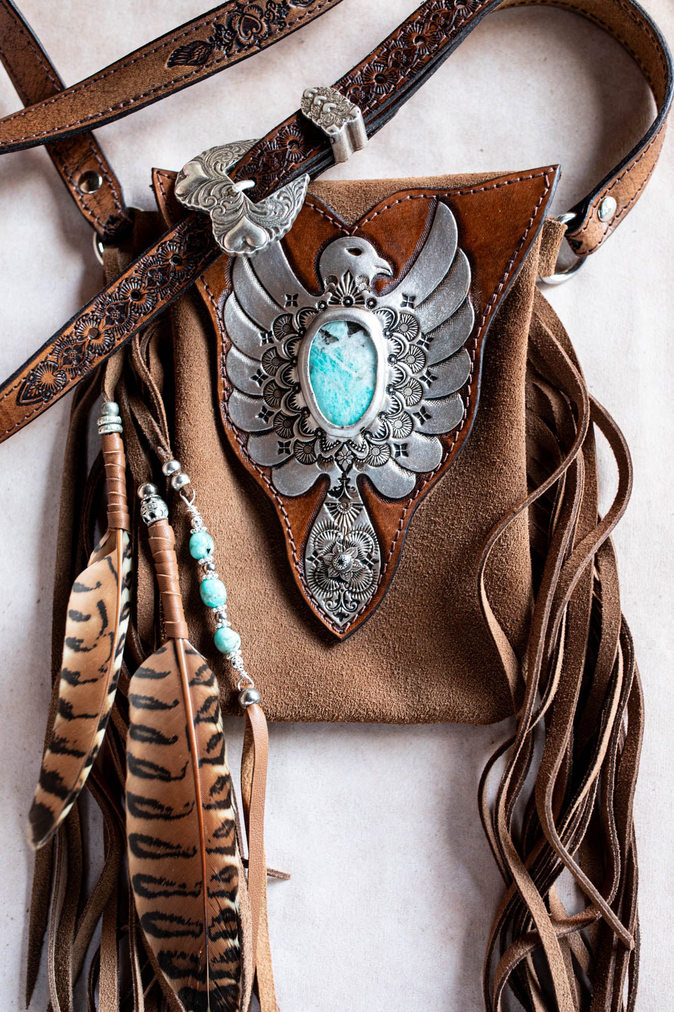 Brown leather bag with eagle design and turquoise stone on a white background